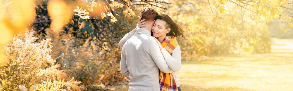 Beautiful couple man woman in love. Boyfriend and girlfriend hugging outdoor in park on autumn fall day. Concept of togetherness and happiness. Banner header for website.