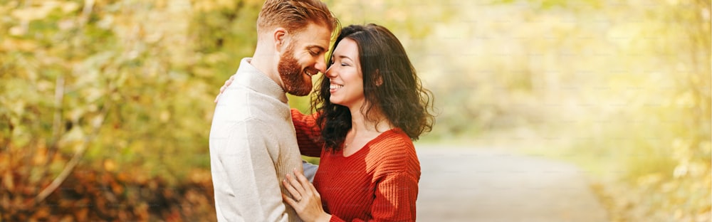 Couple man woman in love. Boyfriend and girlfriend hugging outdoor in park on autumn fall day. Togetherness and happiness. Authentic real people feelings. Banner header for website.