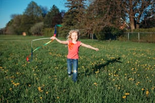 公園でリボンで遊んでいる幸せな子供の女の子。一緒に遊んでいる牧草地を走っているかわいい愛らしい子供。子供のための屋外の夏の裏庭の活動。無邪気な子供時代、率直な本物のライフスタイル。
