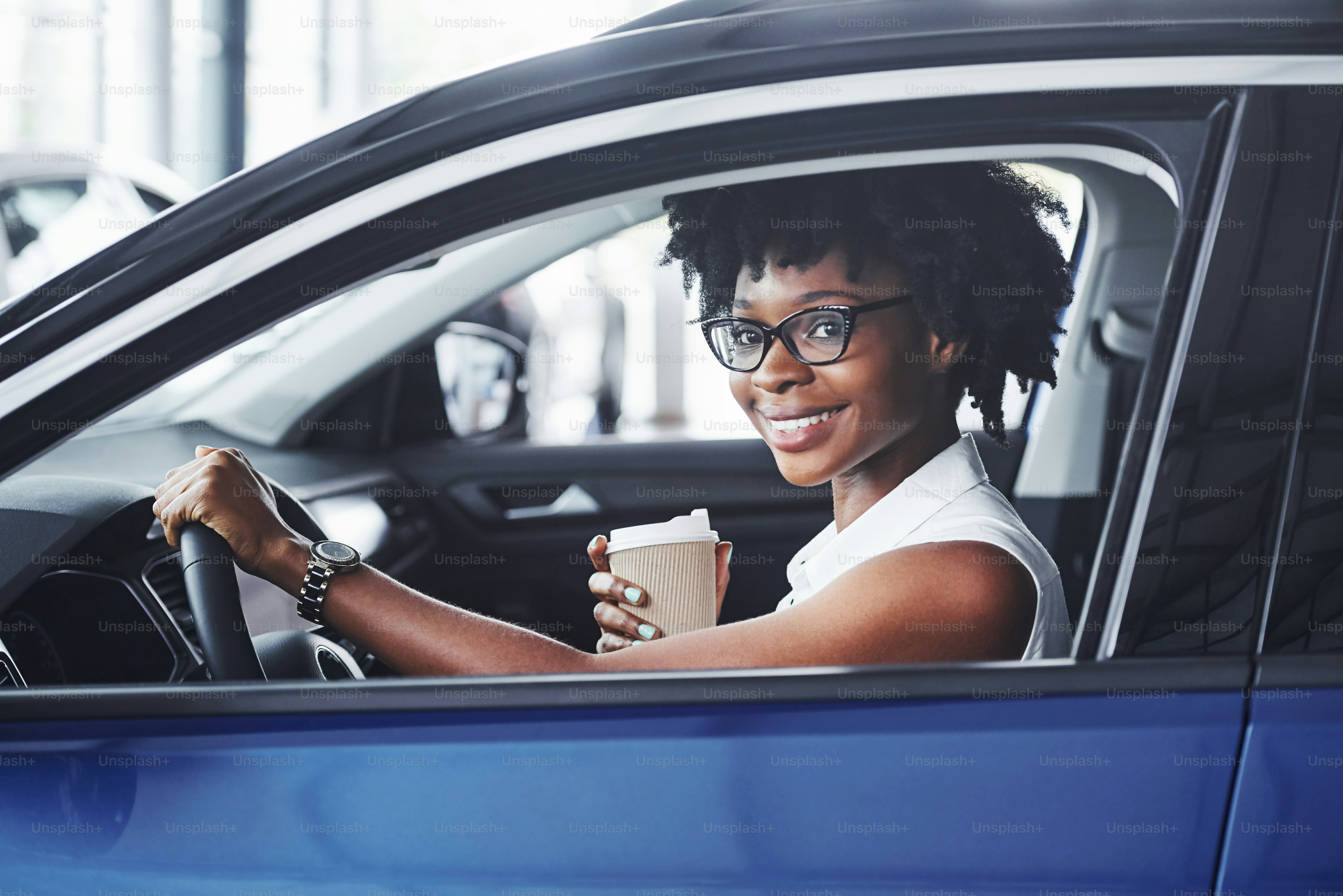 Happy smile. Young african american woman sits inside of new modern car