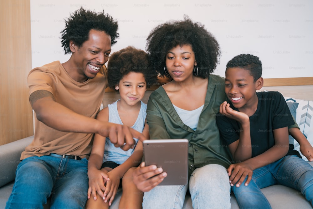 Portrait d’une famille afro-américaine prenant un selfie avec une tablette numérique à la maison. Concept de famille et de style de vie.