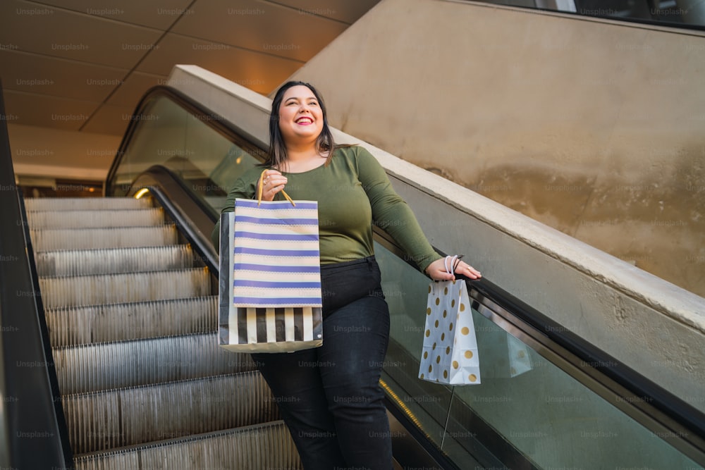 Portrait of young plus size woman holding shopping bags while doing shopping at the mall. Shopping and sale concept.