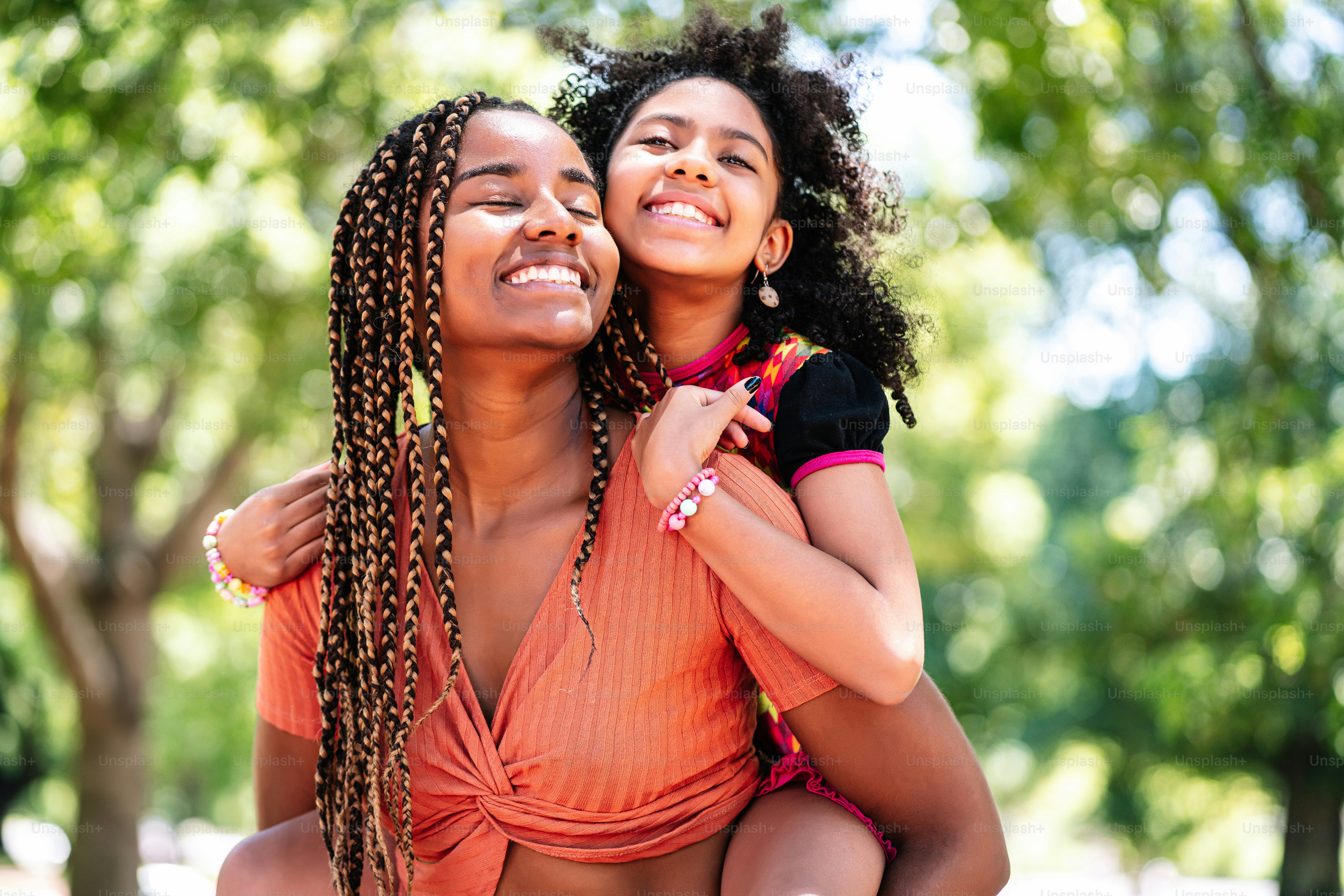 Mother and daughter smiling and enjoying a day together at the park.