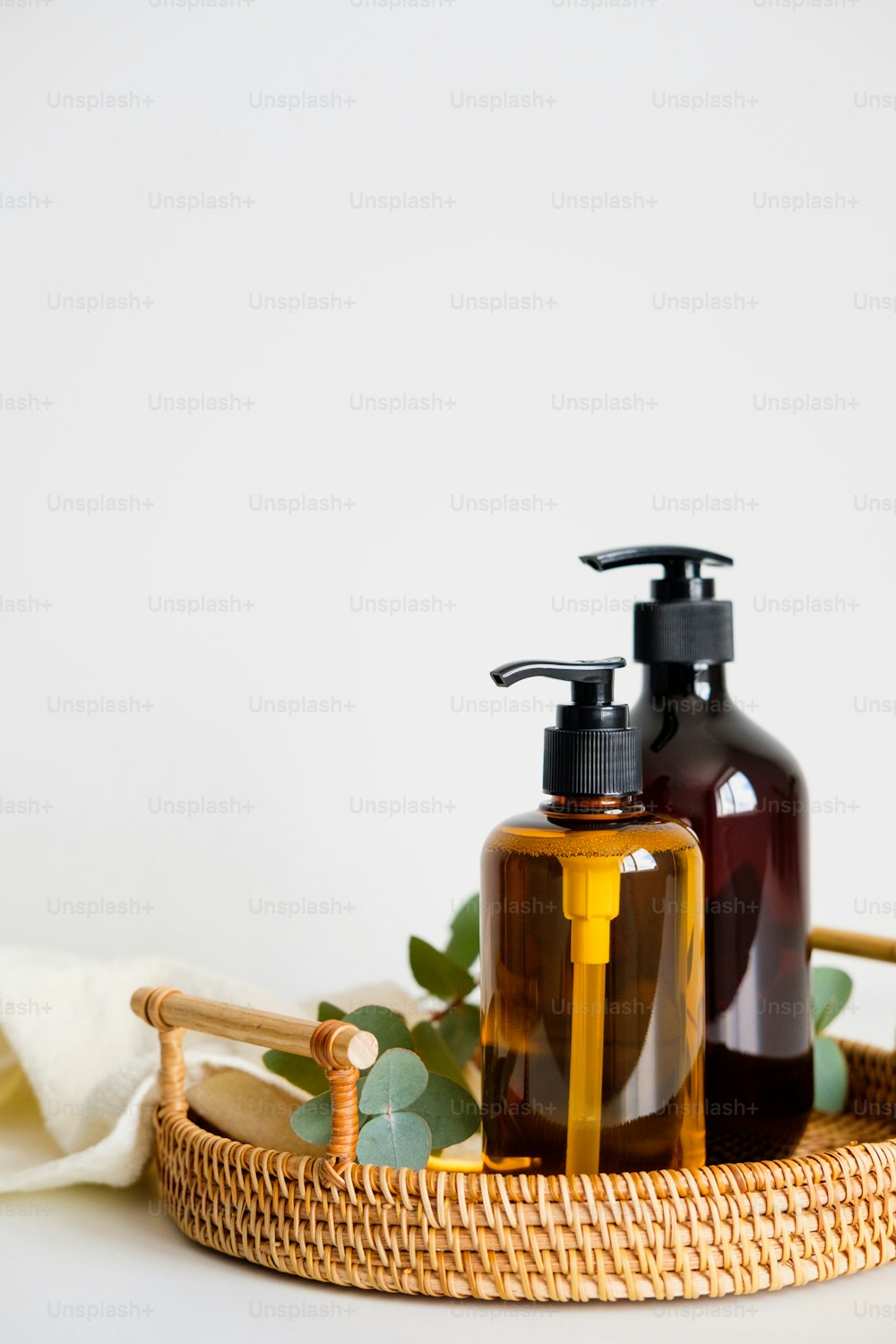 Pump soap dispenser bottles, eucalyptus, towel in rattan tray. SPA organic natural bio cosmetics.