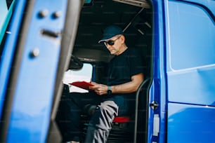 Experienced truck driver sitting in his truck and waiting for a new driving route.