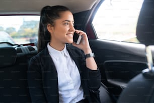 Portrait of business woman talking on phone on way to work in a car. Business concept.