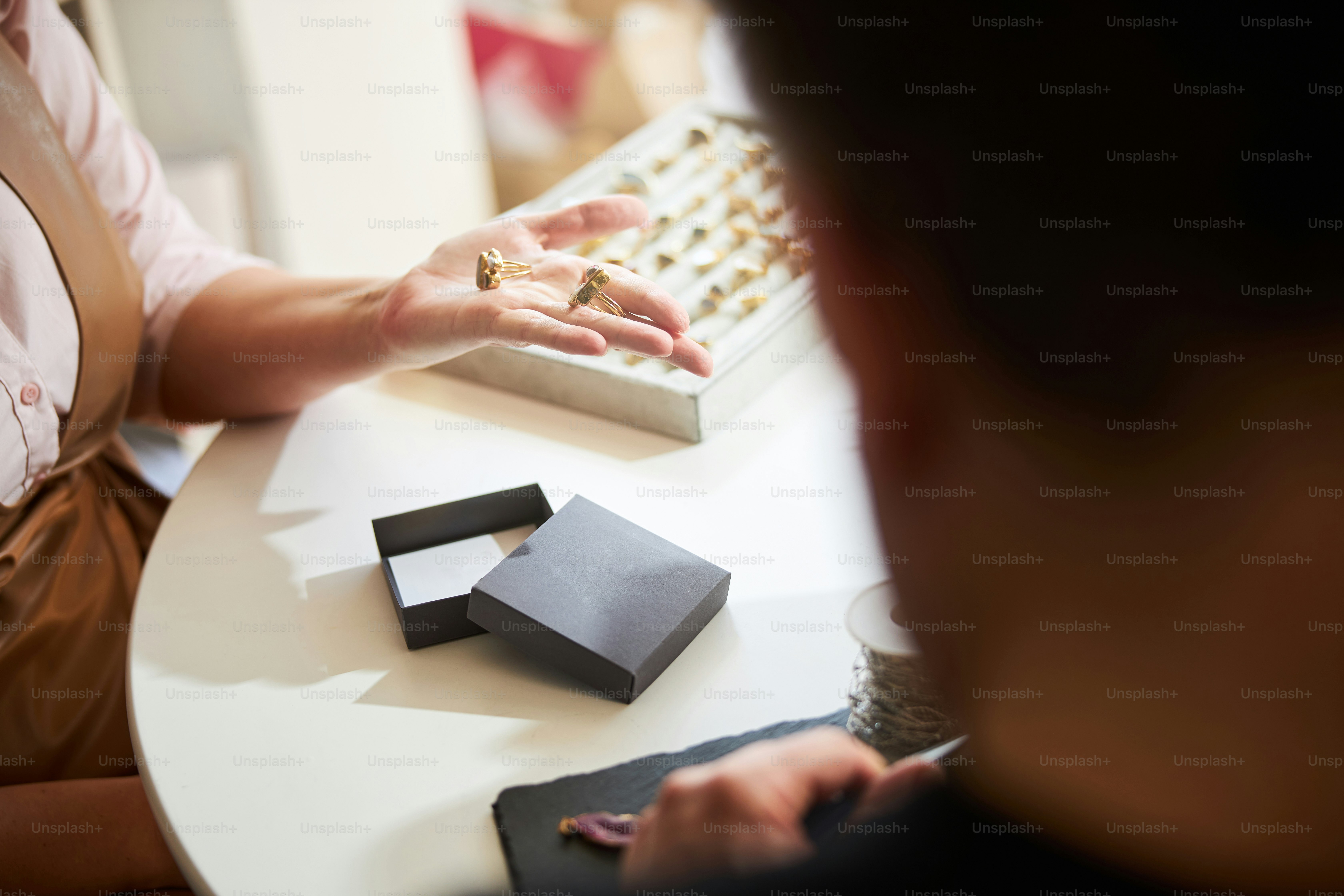 Cropped photo of a female jeweler showing two handcrafted mixed gemstone rings to her male colleague