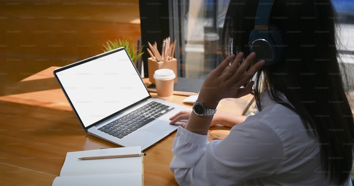 Side view of young woman designer wearing head phone and working on ...