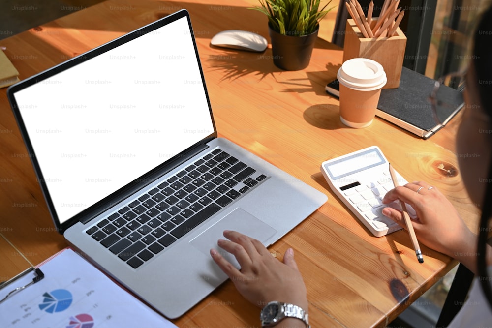 Close up view of female accountant calculating and working on laptop computer at workplace.