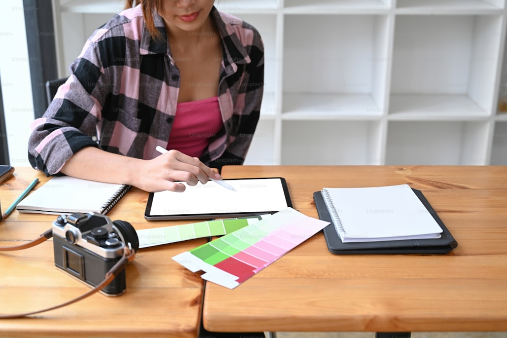Cropped shot of female graphic designer in casual clothes working with digital tablet at office.