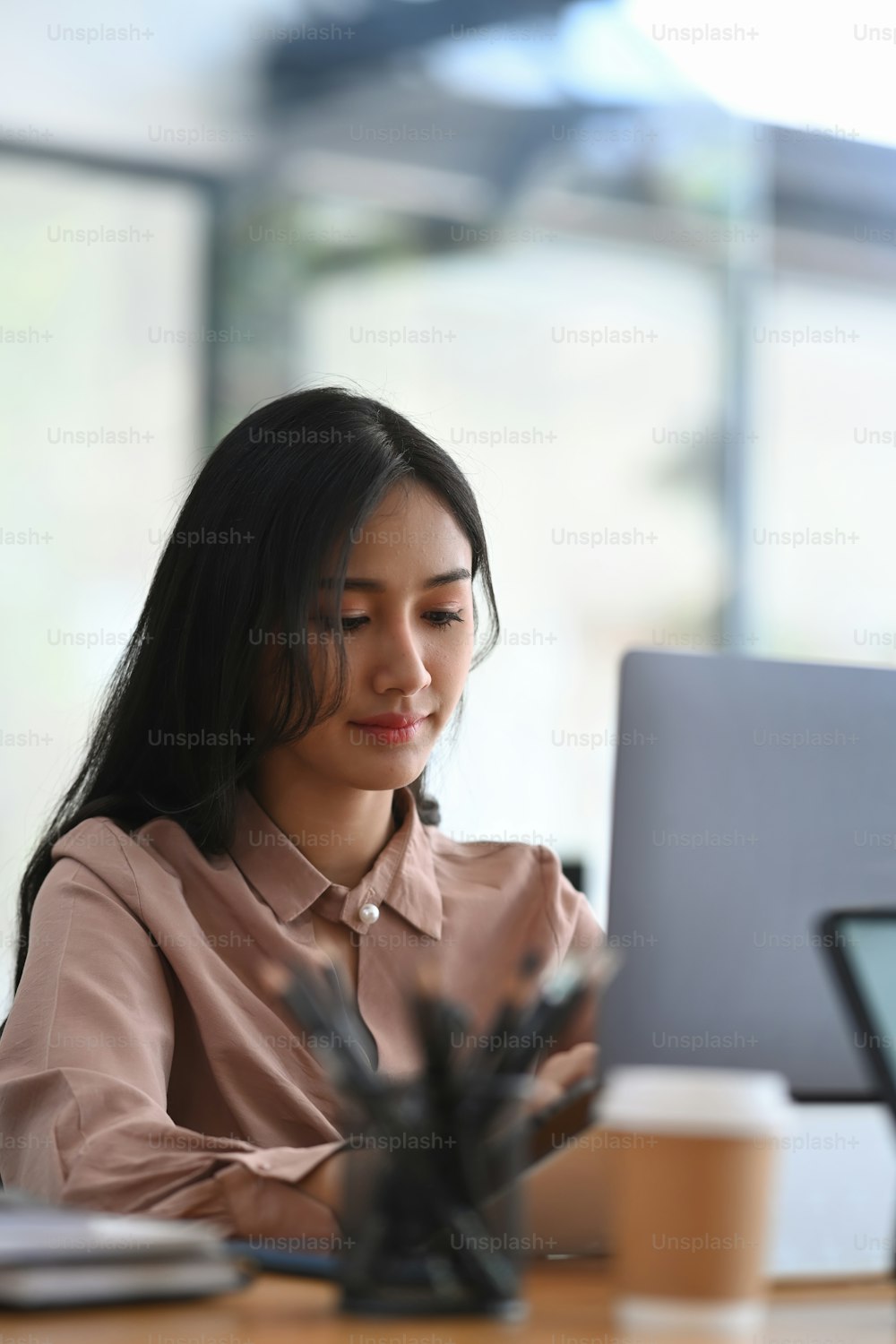 Portrait of businesswoman sitting in modern workplace and looking business data on digital tablet.