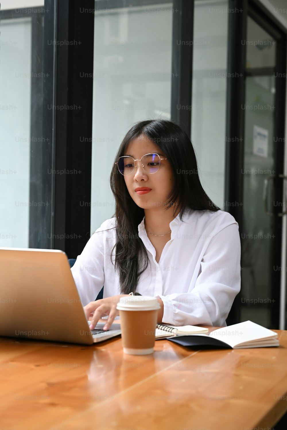 Portrait of businesswoman sitting in modern office and checking email on laptop computer.