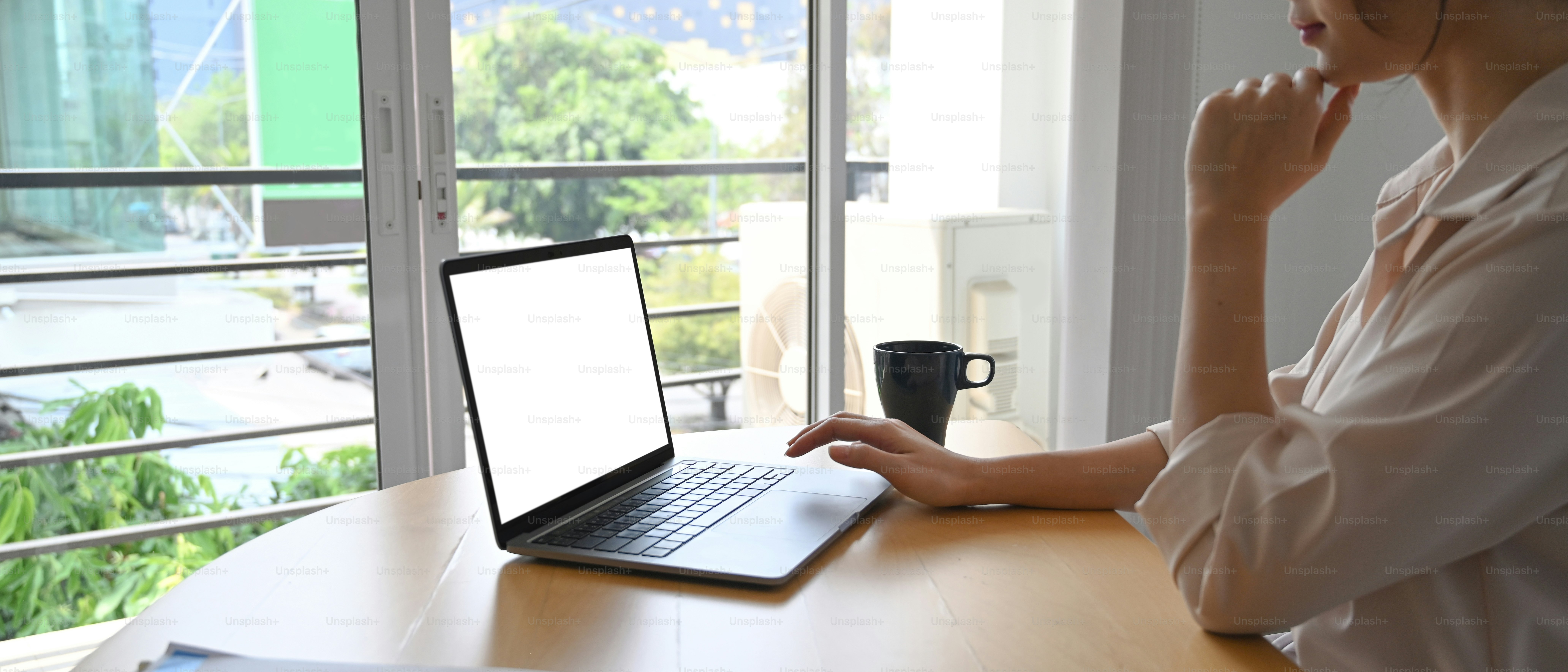 Vista laterale della donna d'affari che utilizza il computer portatile che naviga in internet in ufficio.