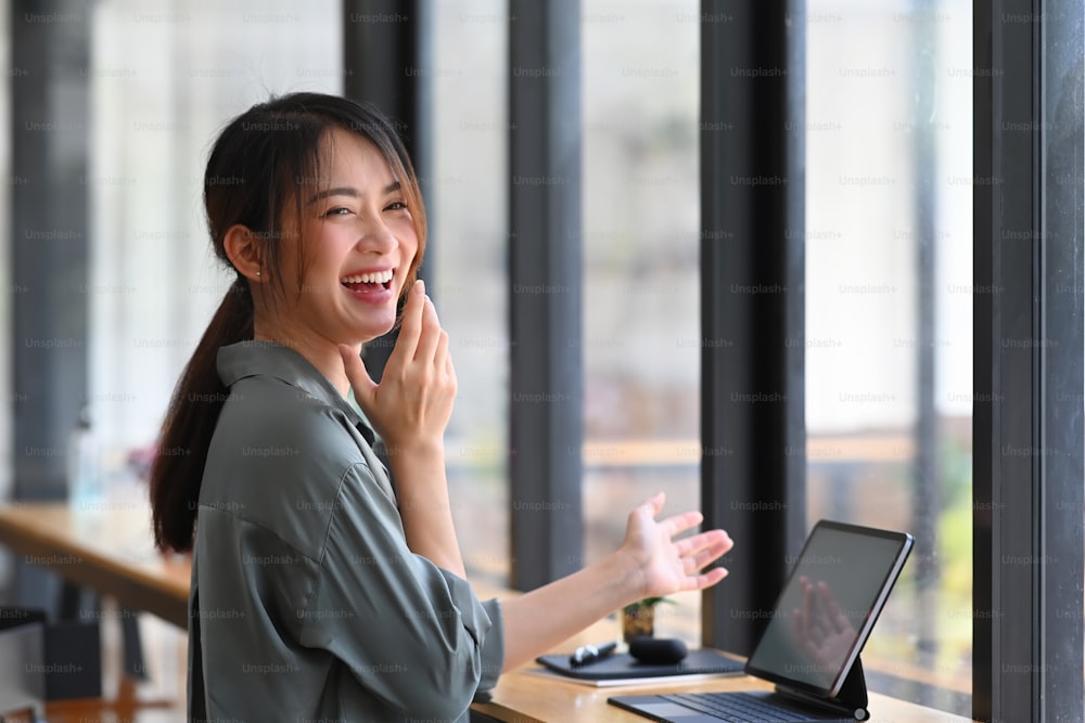 Happy young woman laughing while sitting at workplace.