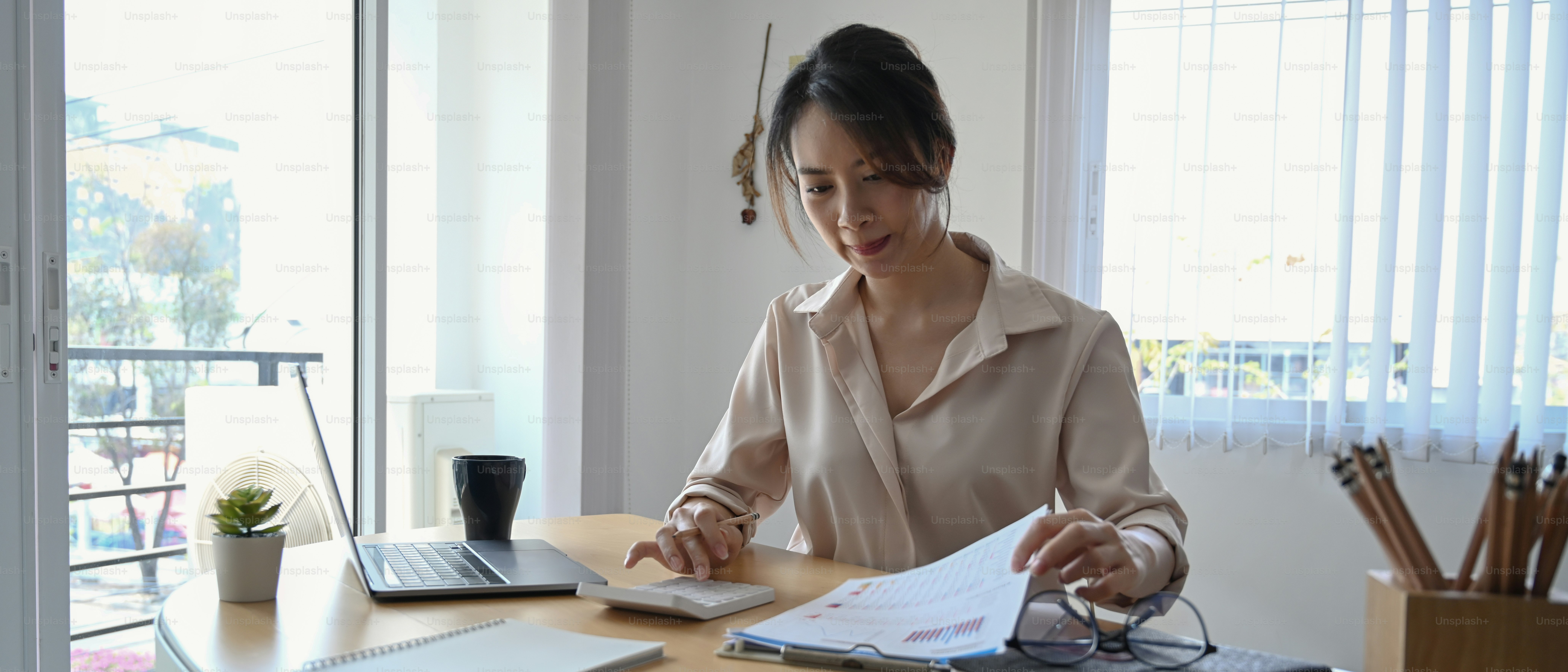 Businesswoman using calculator and analyzing financial report at office