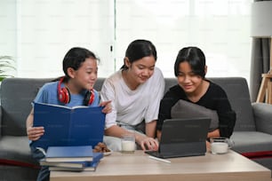 Three asian girl using digital tablet and sitting together on sofa in living room.