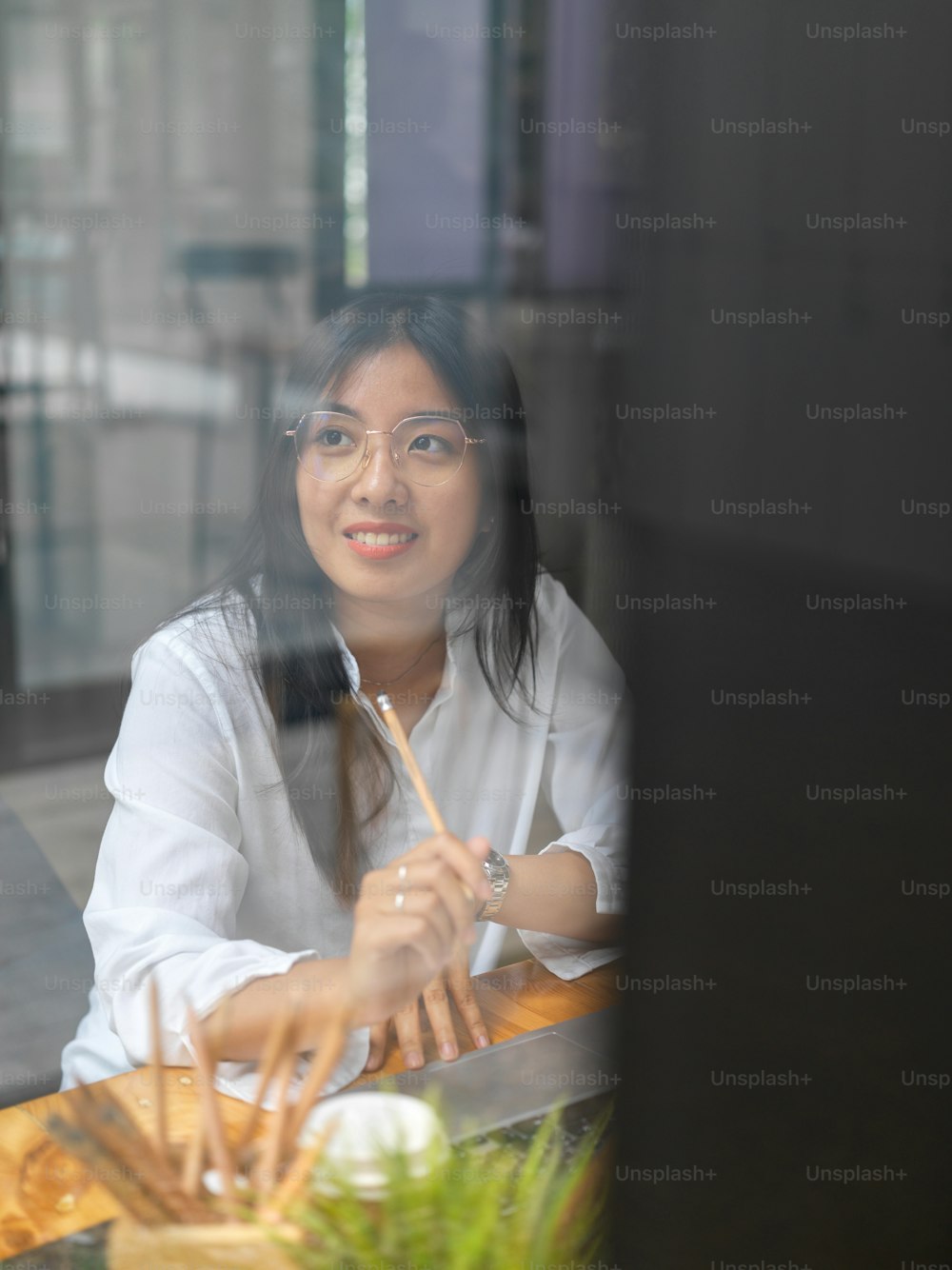 View through glass wall of female worker smiling and enjoying with the view out of workplace window