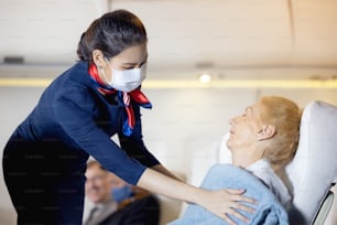 여성 승무원이 조수석에서 자고있는 노인 승객에게 옷을 입혔습니다. 승객을 돌보는 스튜어디스. 객실 승무원은 비행기 승객에게 서비스를 제공합니다.