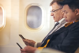 Mann, der mit dem Flugzeug reist und Mobiltelefon benutzt, Konzept Internet in der Luftstratosphäre