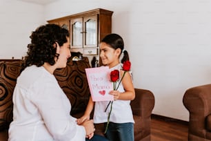 Happy mother's day, Mexican Child daughter congratulates mom and gives her flowers at home in Mexico city