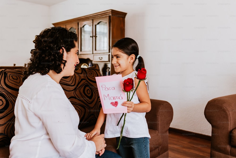 Feliz día de las madres, hija de la niña mexicana felicita a mamá y le regala flores en su casa en la ciudad de México
