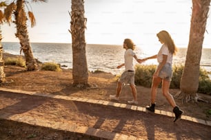 Beautiful couple walking on the ocean coast, holding hands, enjoying sunset time together. Real people emotions and love concept.