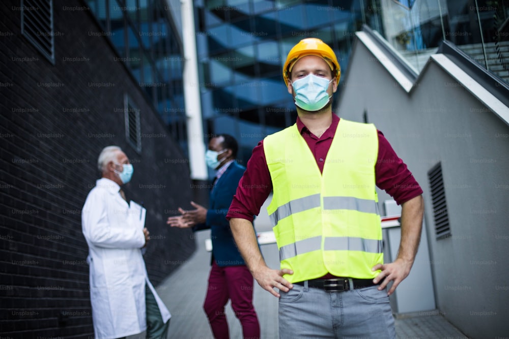 Three men, a doctor, a business man and and engineer standing on street. Focus is on man with helmet.