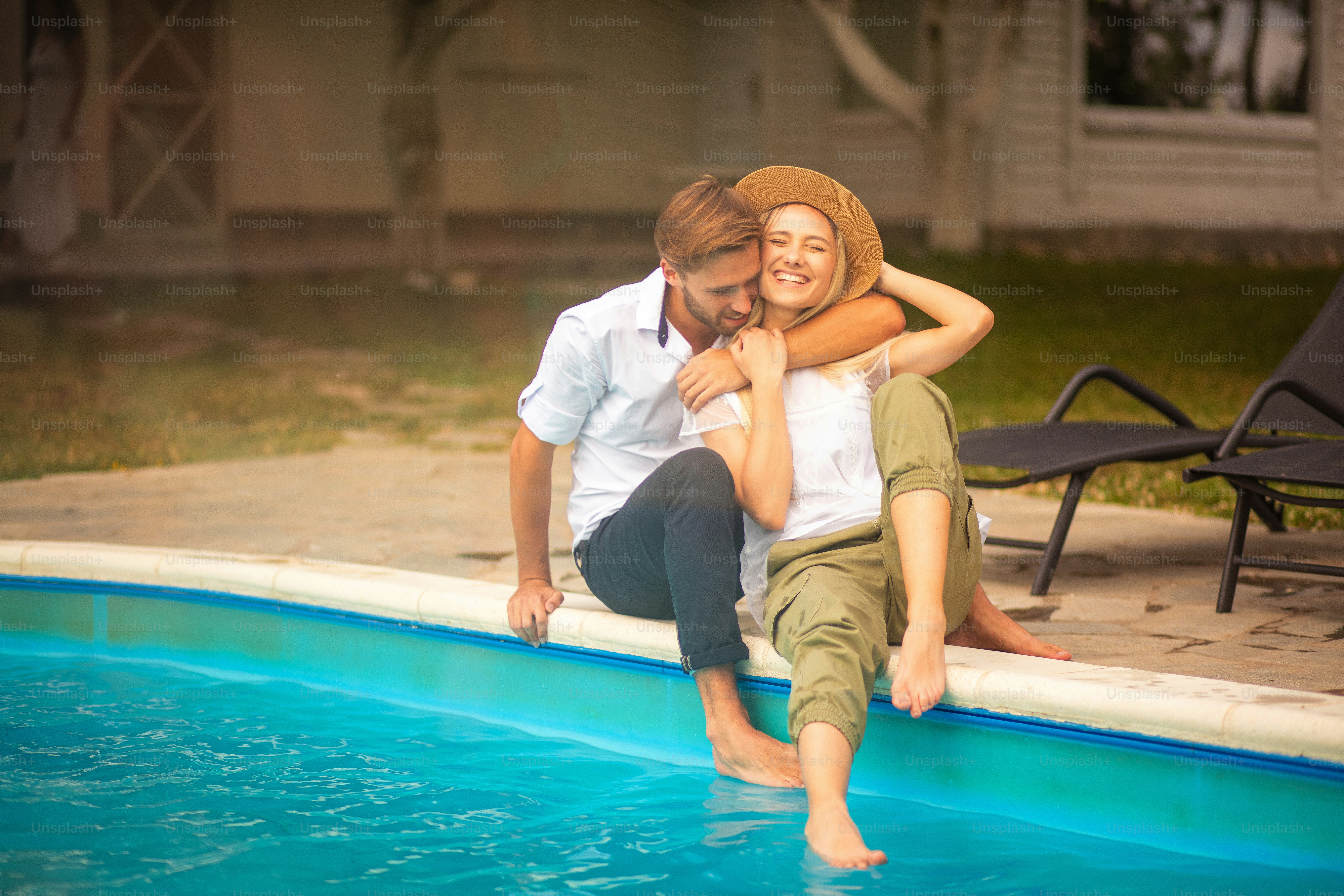Happy smiling couple sitting by the pool.