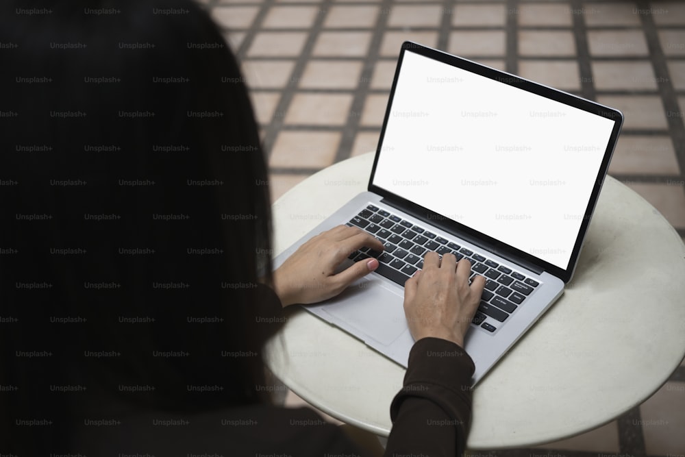 Close up over shoulder view of businesswoman sitting outdoor and working with laptop computer.