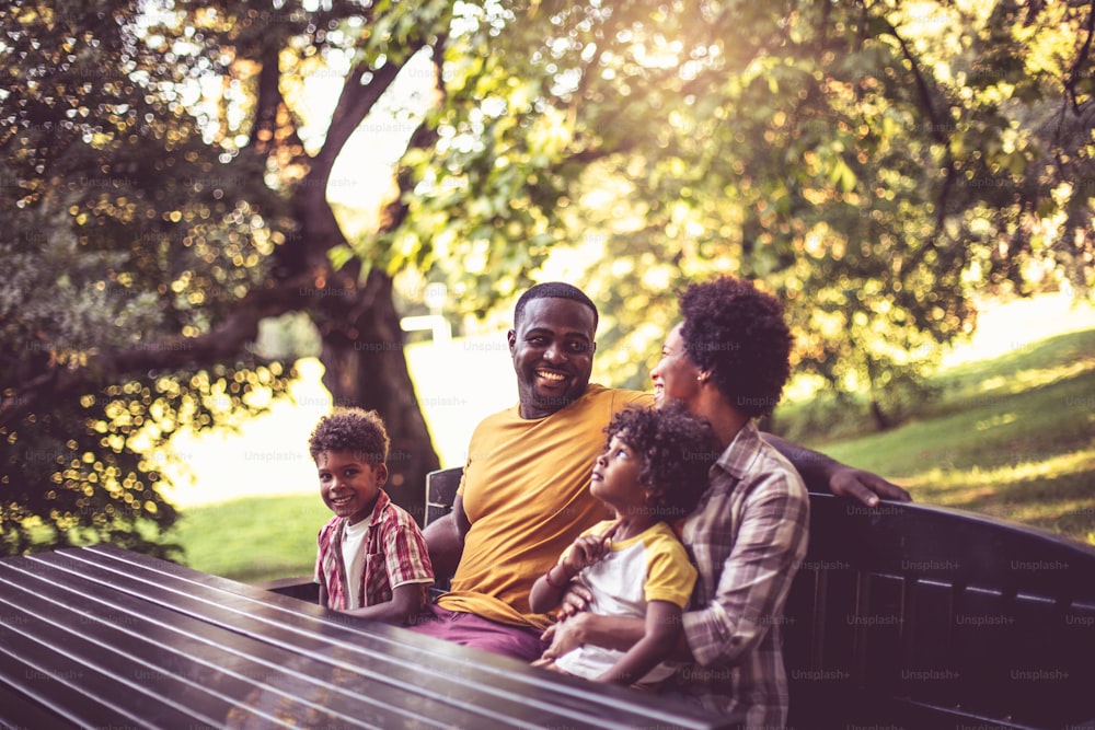 公園のベンチに座っているアフリカ系アメリカ人の家族。