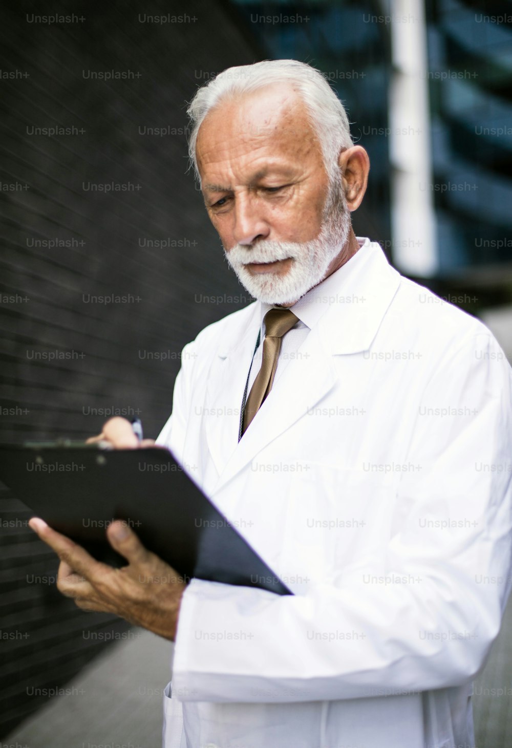 Senior doctor standing on street and writing on document.