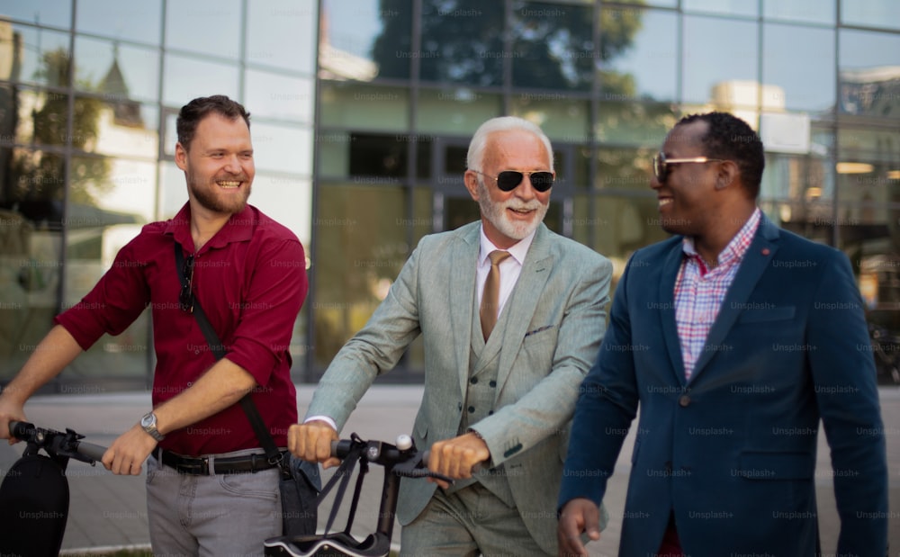 Tre uomini d'affari sulla strada. Due uomini con scooter elettrico.