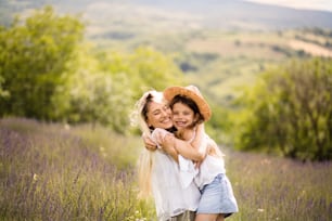 Mother and daughter  stands in lavender field. Mother and daughter in hug.
