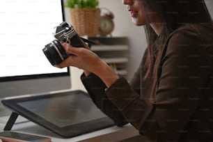 Cropped shot of professional female photographer checking pictures previews on camera.