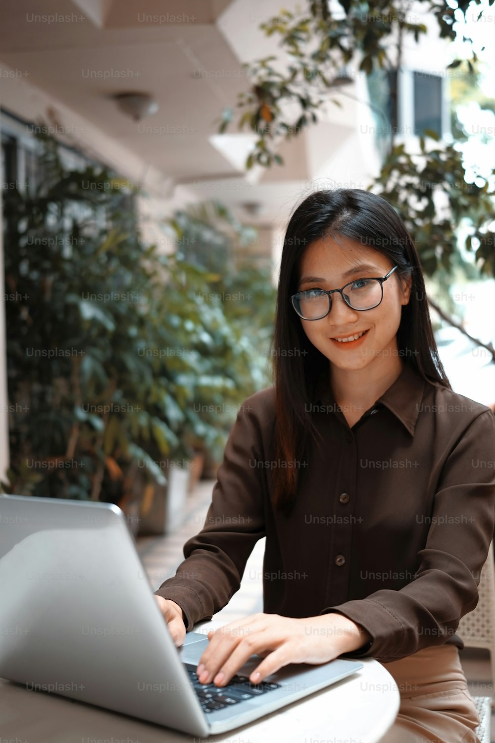 Retrato de una mujer de negocios sonriente sentada al aire libre y trabajando con una computadora portátil.
