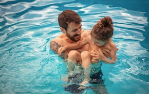 Father and son playing together in the swimming pool.