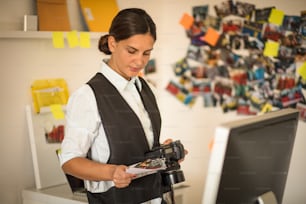 FBI woman with camera in office. Holding photos. Close up.