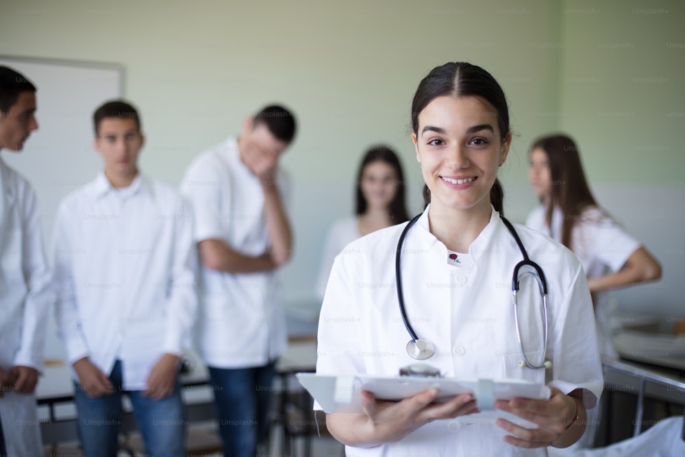 Female student holding patient results.  Medical students in patient's hospital room. Focus is on foreground. Looking at camera.