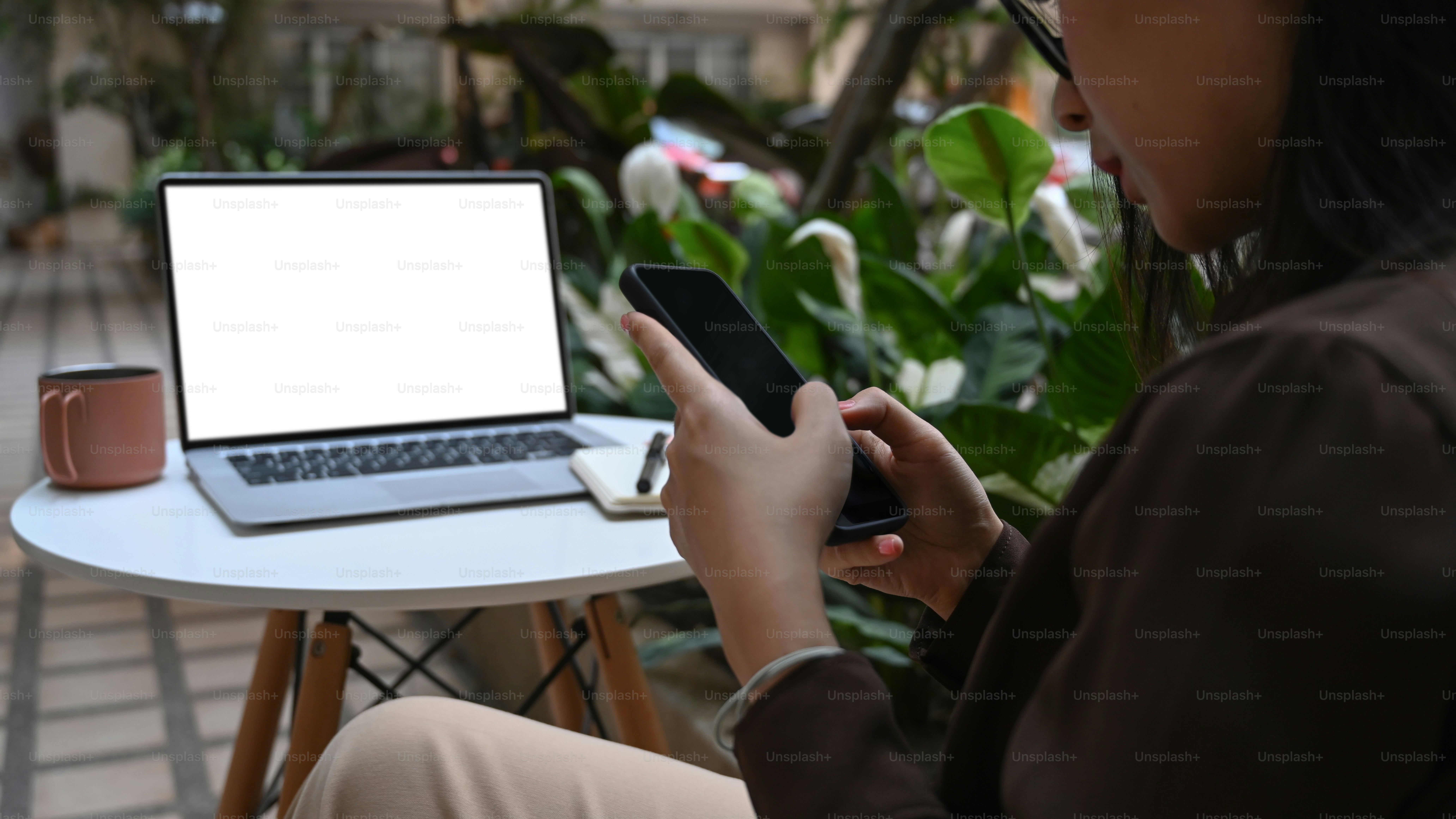 Cropped shot of young woman sitting at outdoor cafe and texting or massaging on mobile phone.
