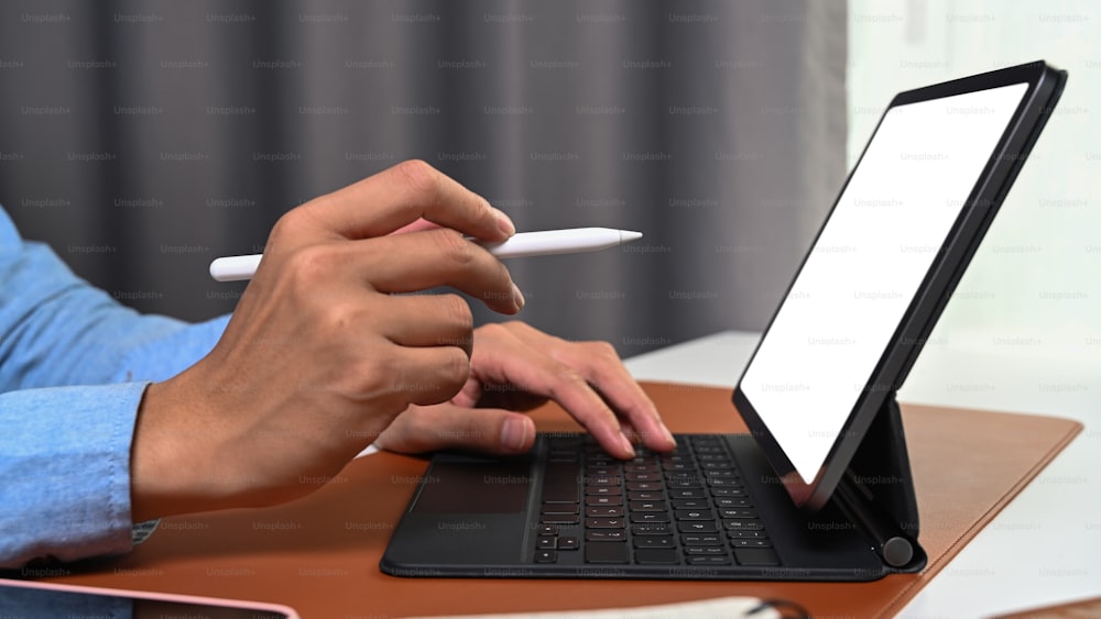 Vista ravvicinata mano dell'uomo d'affari che tiene la penna stilo che punta sullo schermo del tablet del computer.