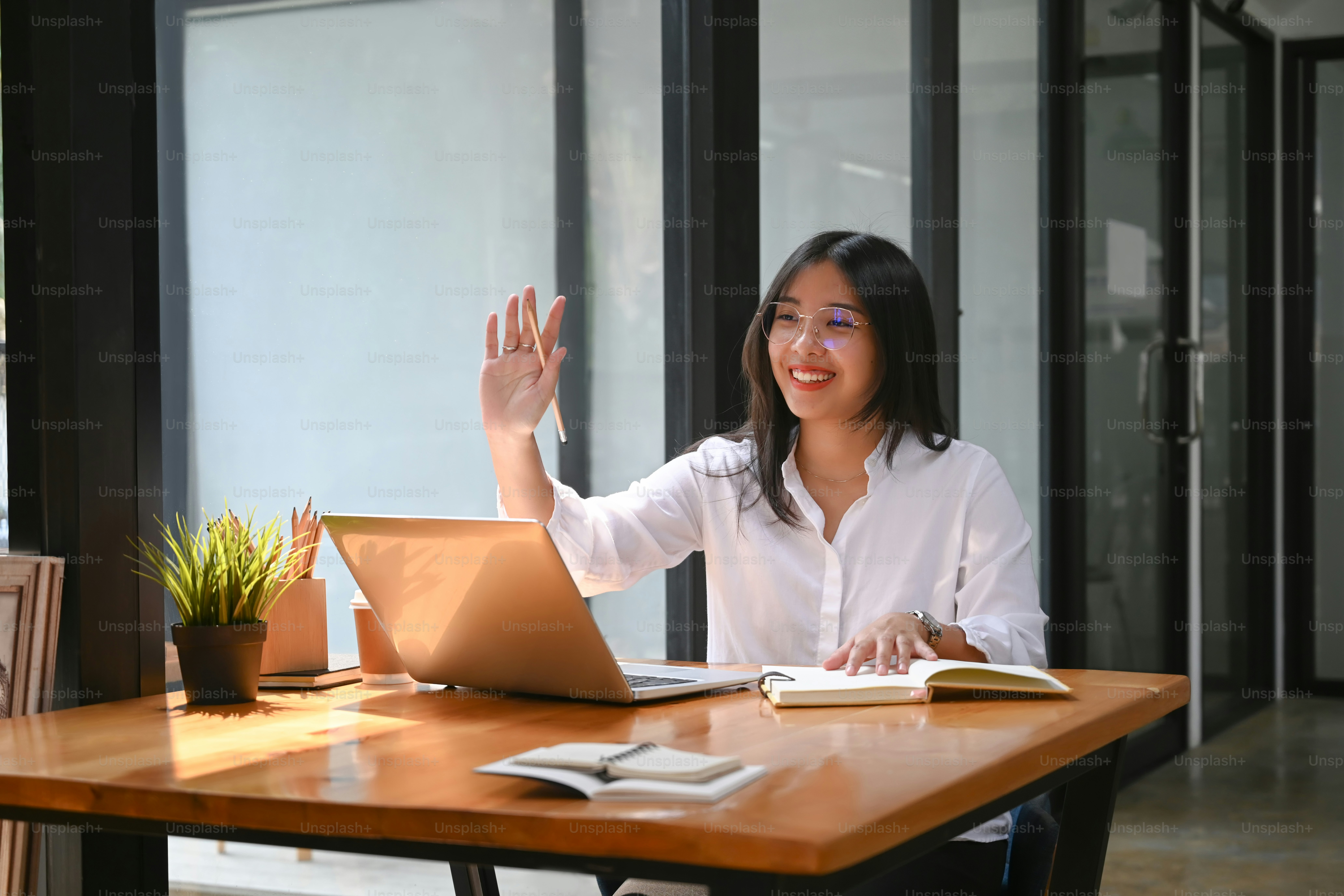 Happy young woman having video call via laptop computer with her  colleagues in office.