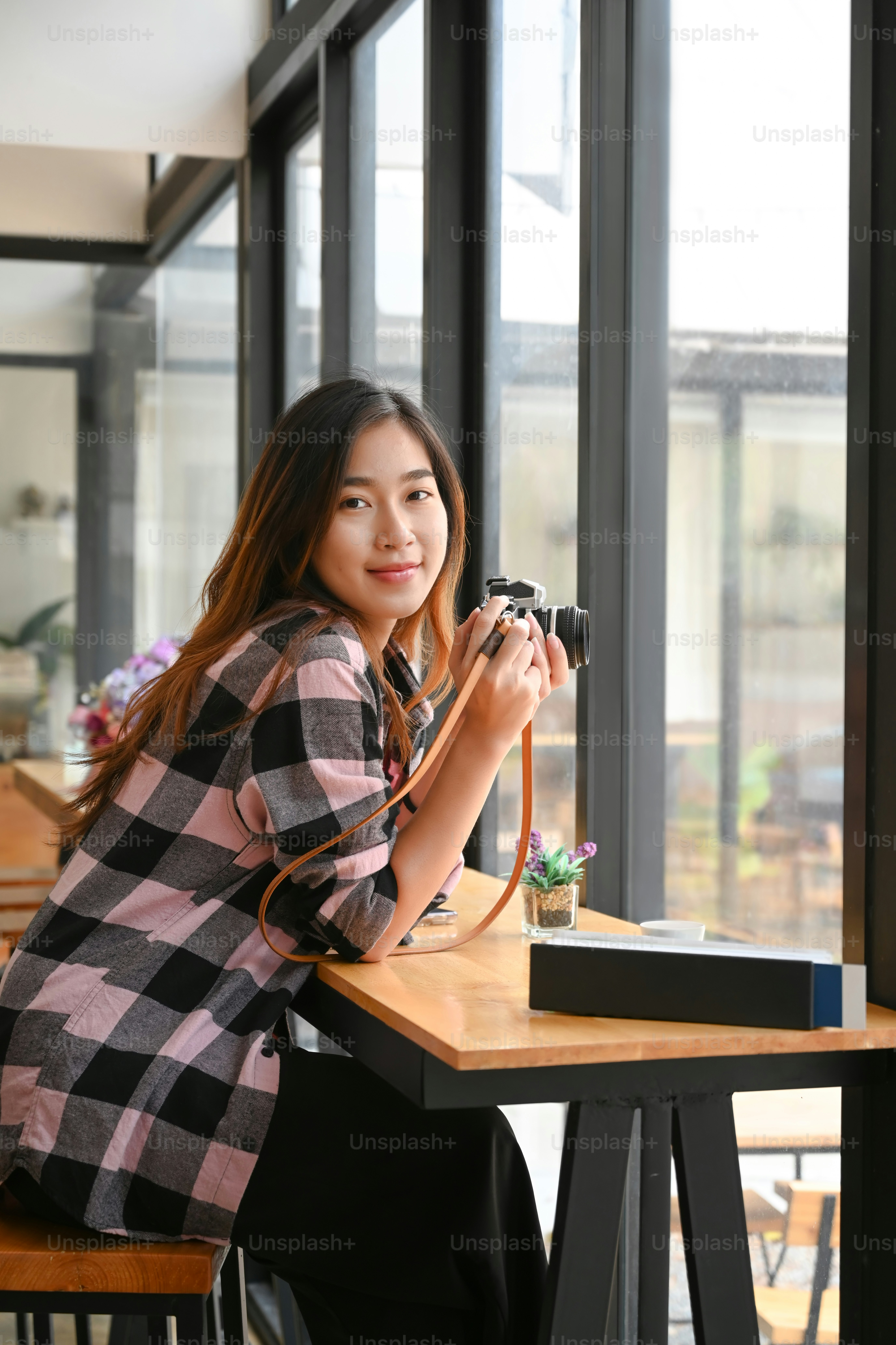 Retrato de una fotógrafa joven y alegre sosteniendo su cámara digital y sonriendo a la cámara.