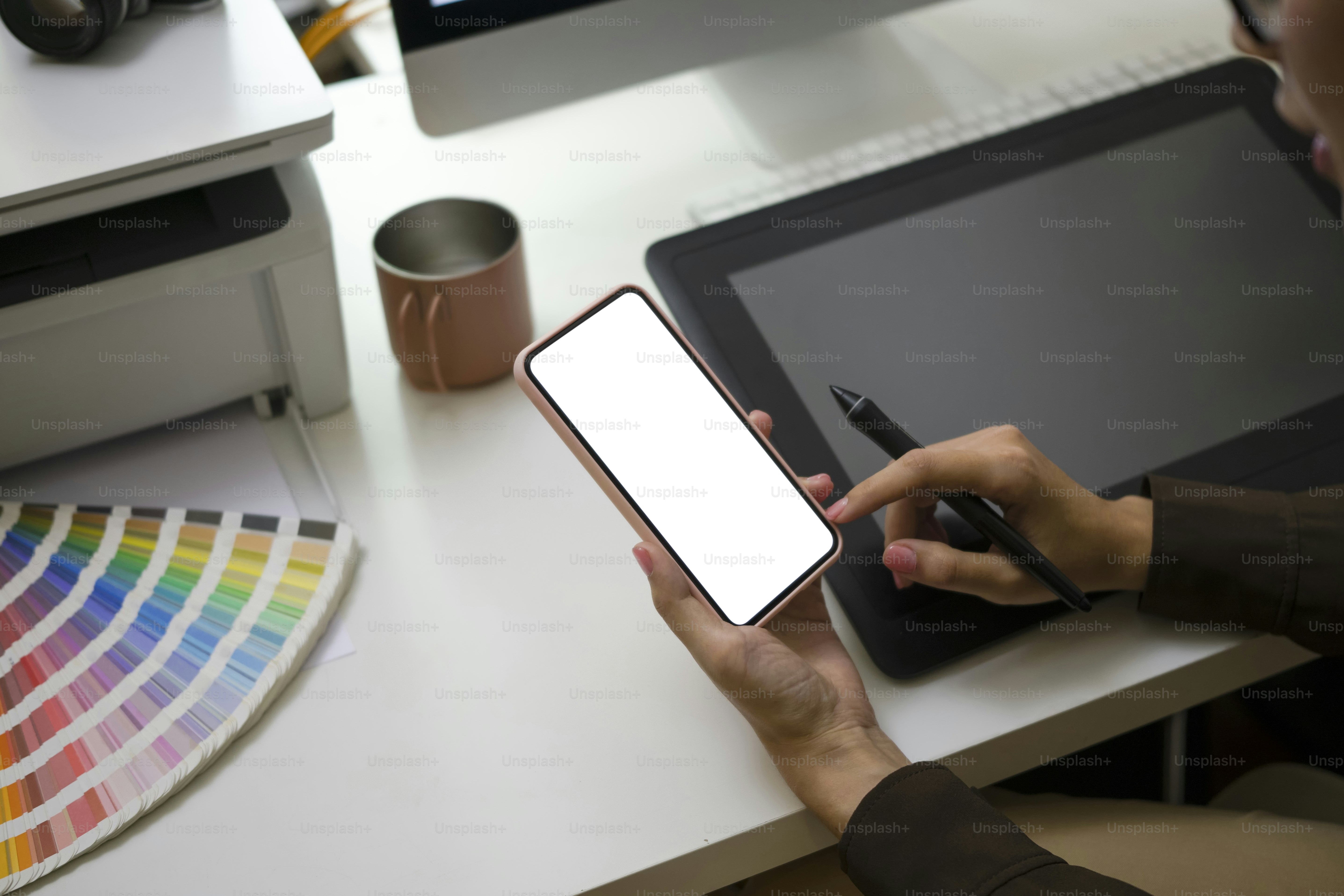 Cropped shot of female graphic designer sitting at her workplace and using smart phone.