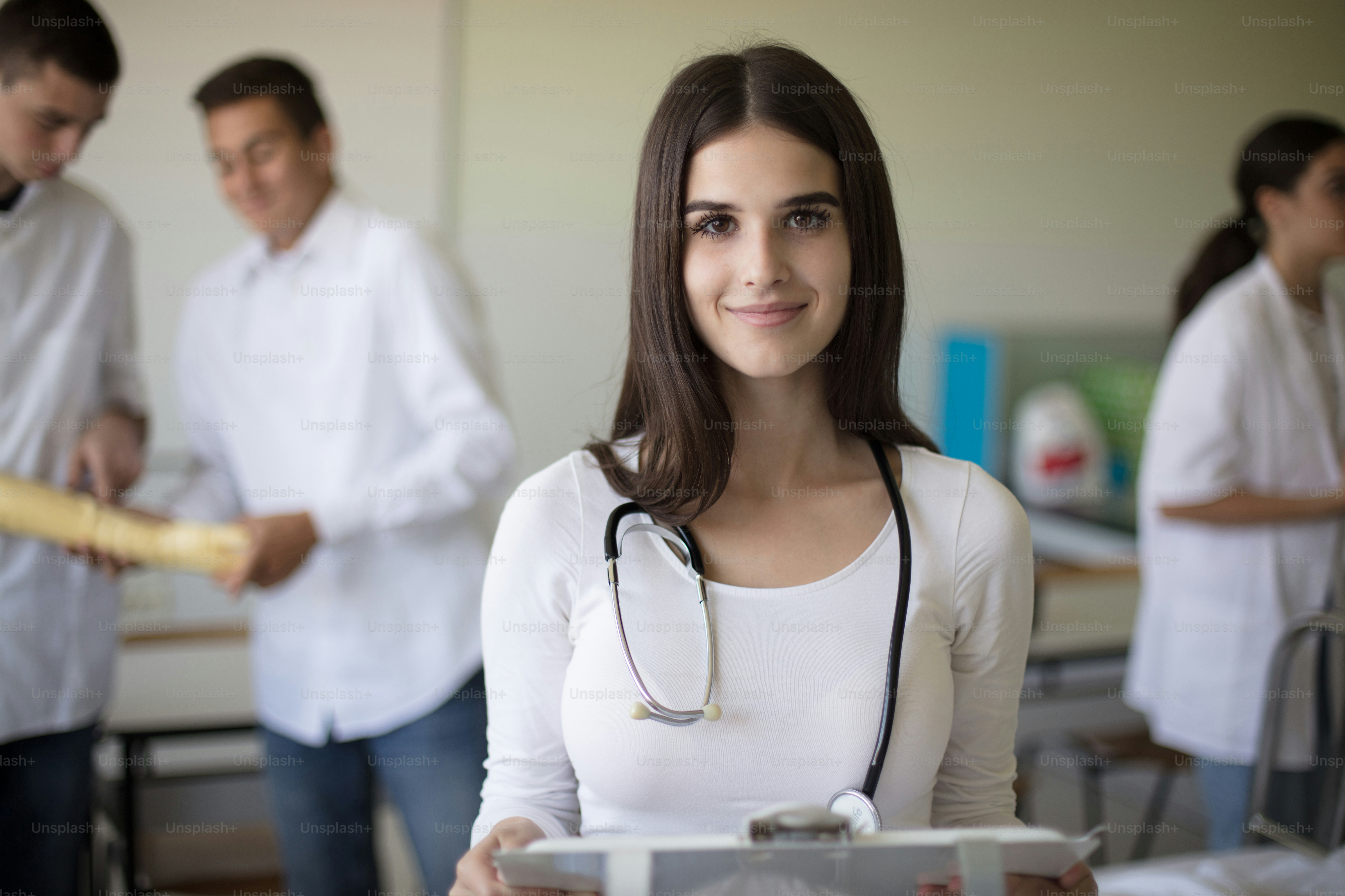 Young female student holding patient results.  Medical students in patient's hospital room. Focus is on foreground. Looking at camera.