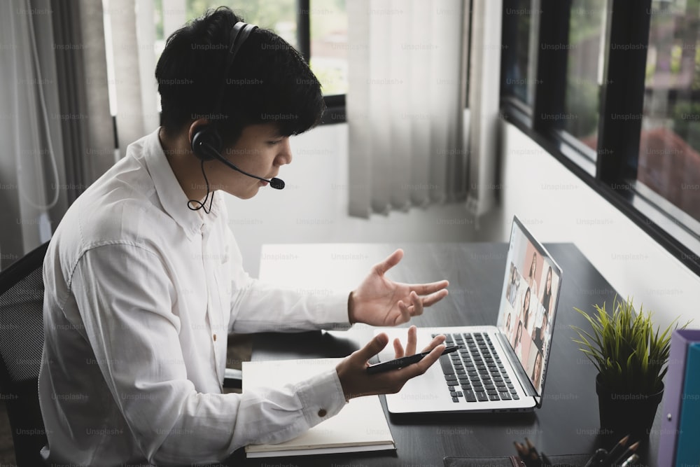 Side view of businessman using laptop computer and  talking to his diverse colleagues in video conference.