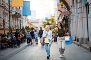 Two women on street carrying shopping bags.