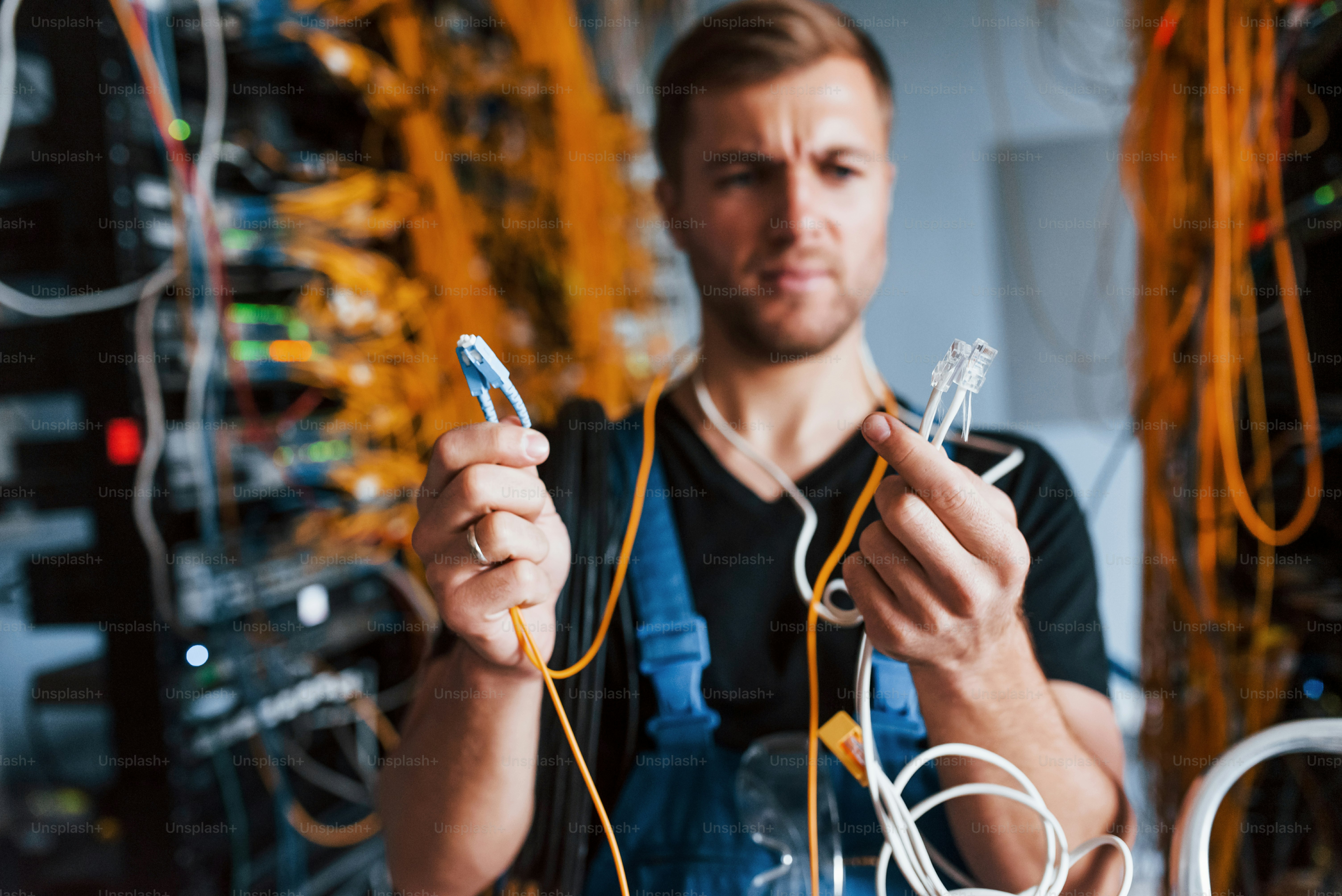 Jovem de uniforme se sente confuso e procura uma solução com equipamentos de internet e fios na sala do servidor