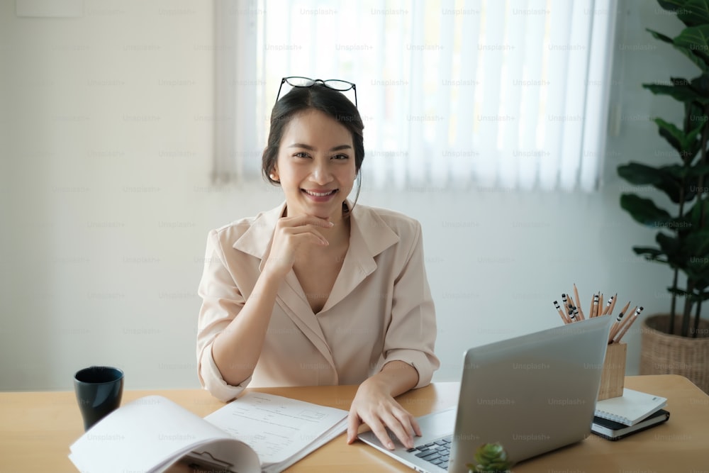 Portrait of happy woman sitting at her office. Attractive young confident business woman or accountant smiling and have idea for her big project