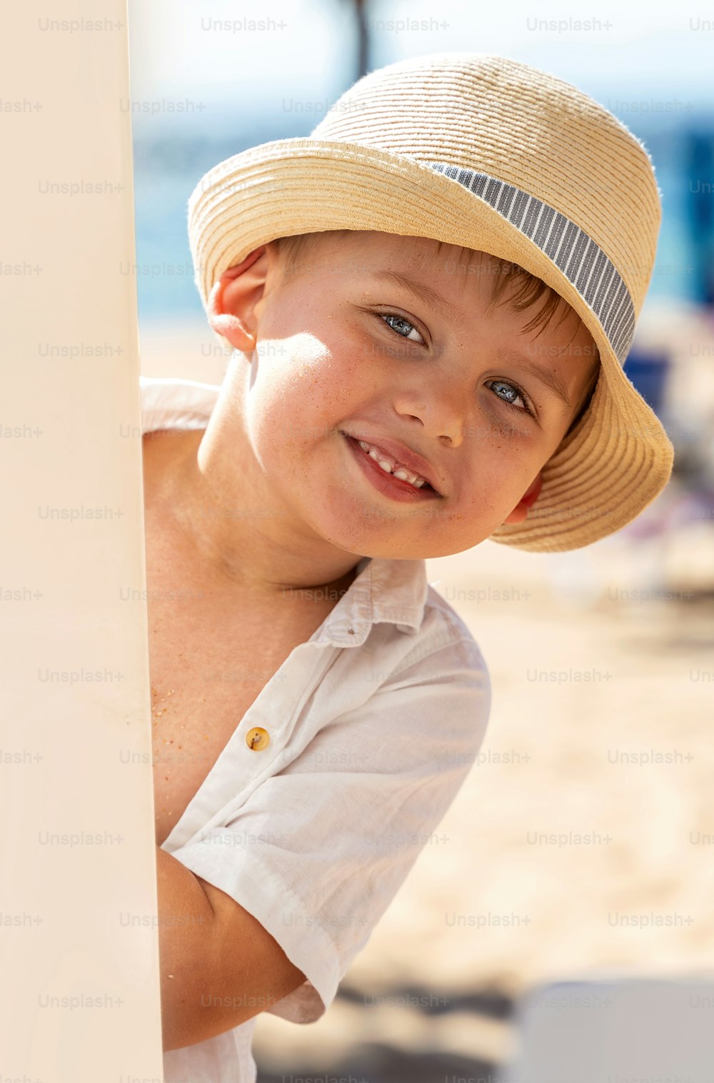 모래 열대 해변에서 놀고 있는 모자를 쓴 웃는 어린 소년. 여름 분위기. 많은 복사 공간.