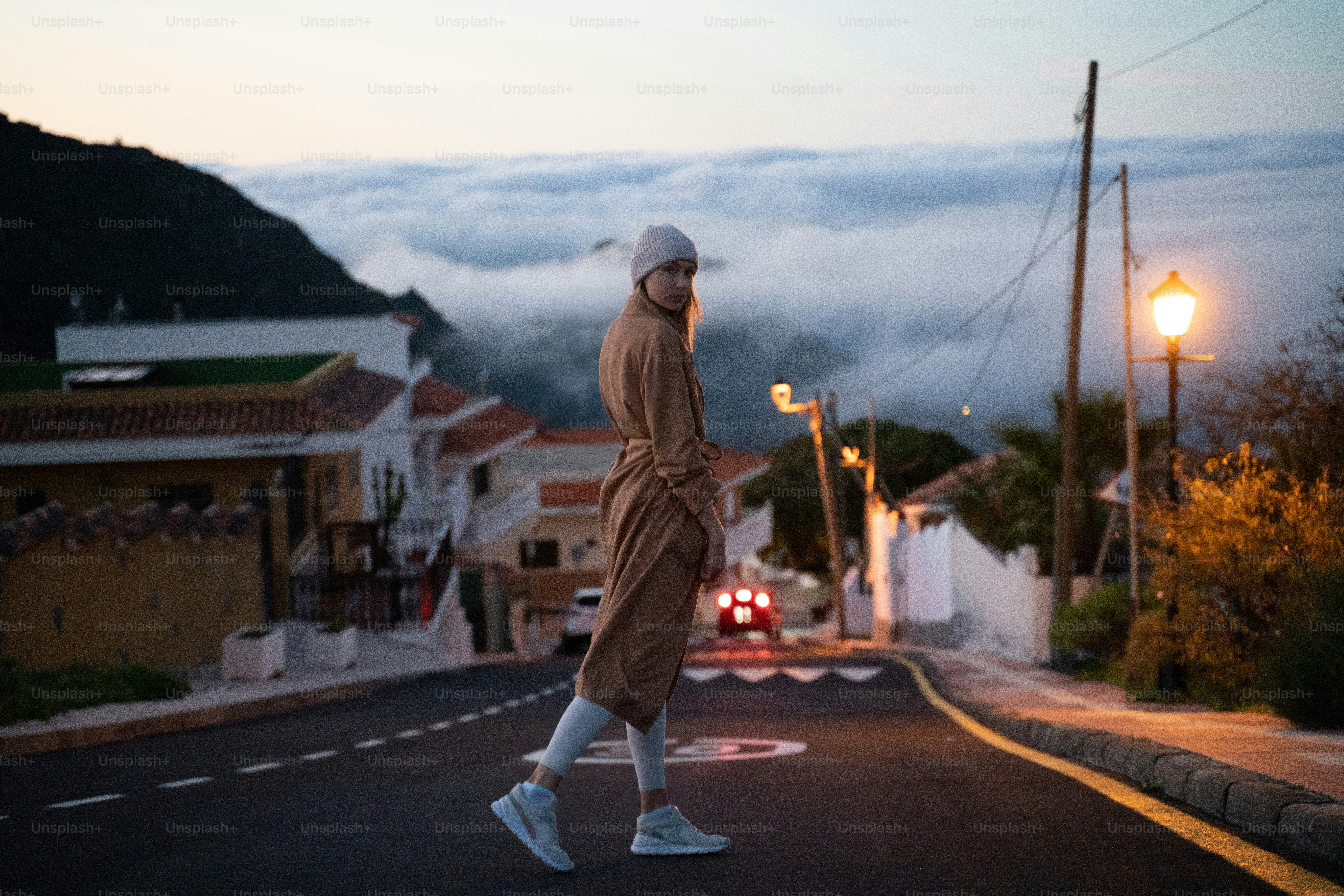 Vintage photo of woman walking on the hilly village road on the morning, before the sunrise, looking at camera.